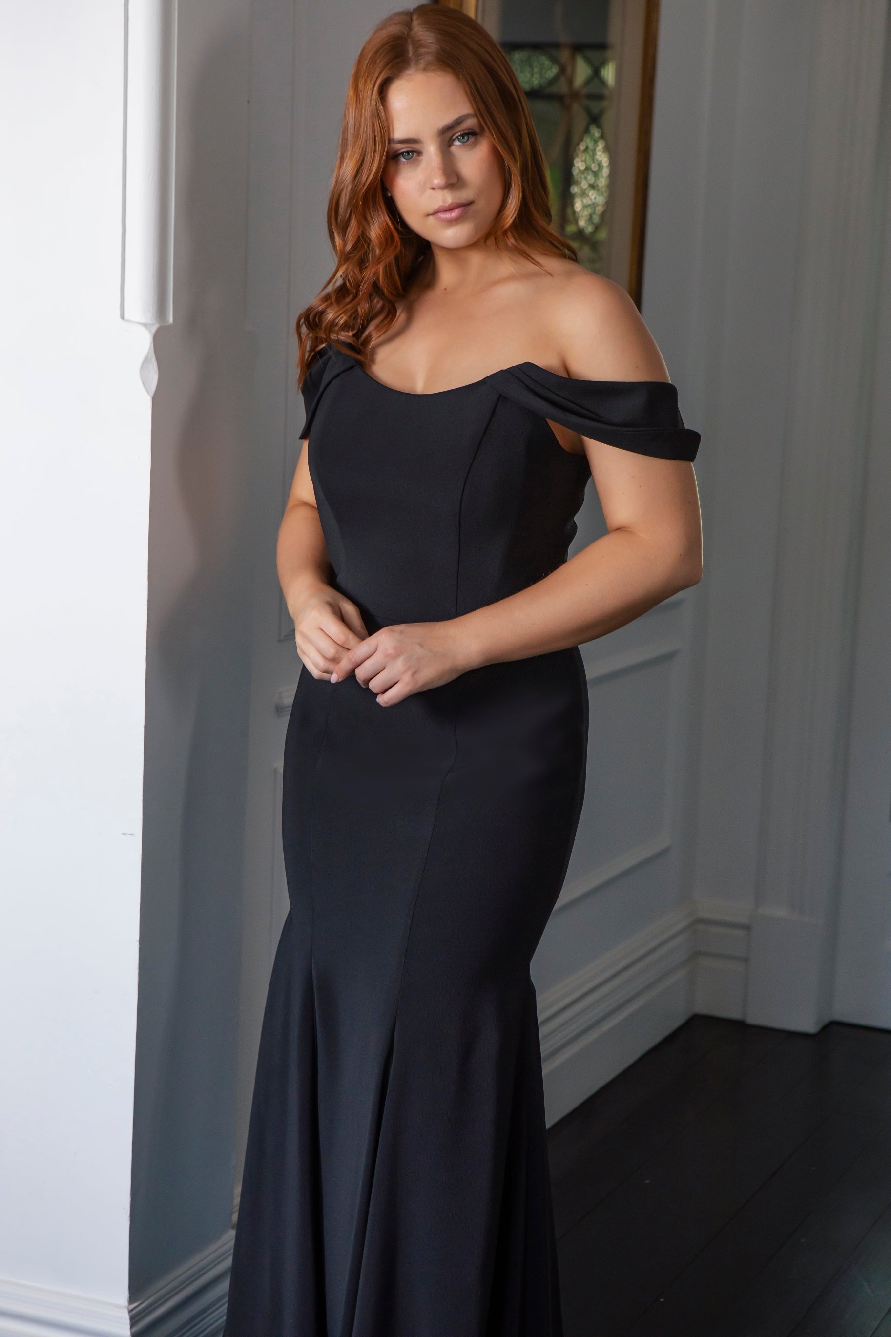 Woman wearing a black off-shoulder dress indoors.