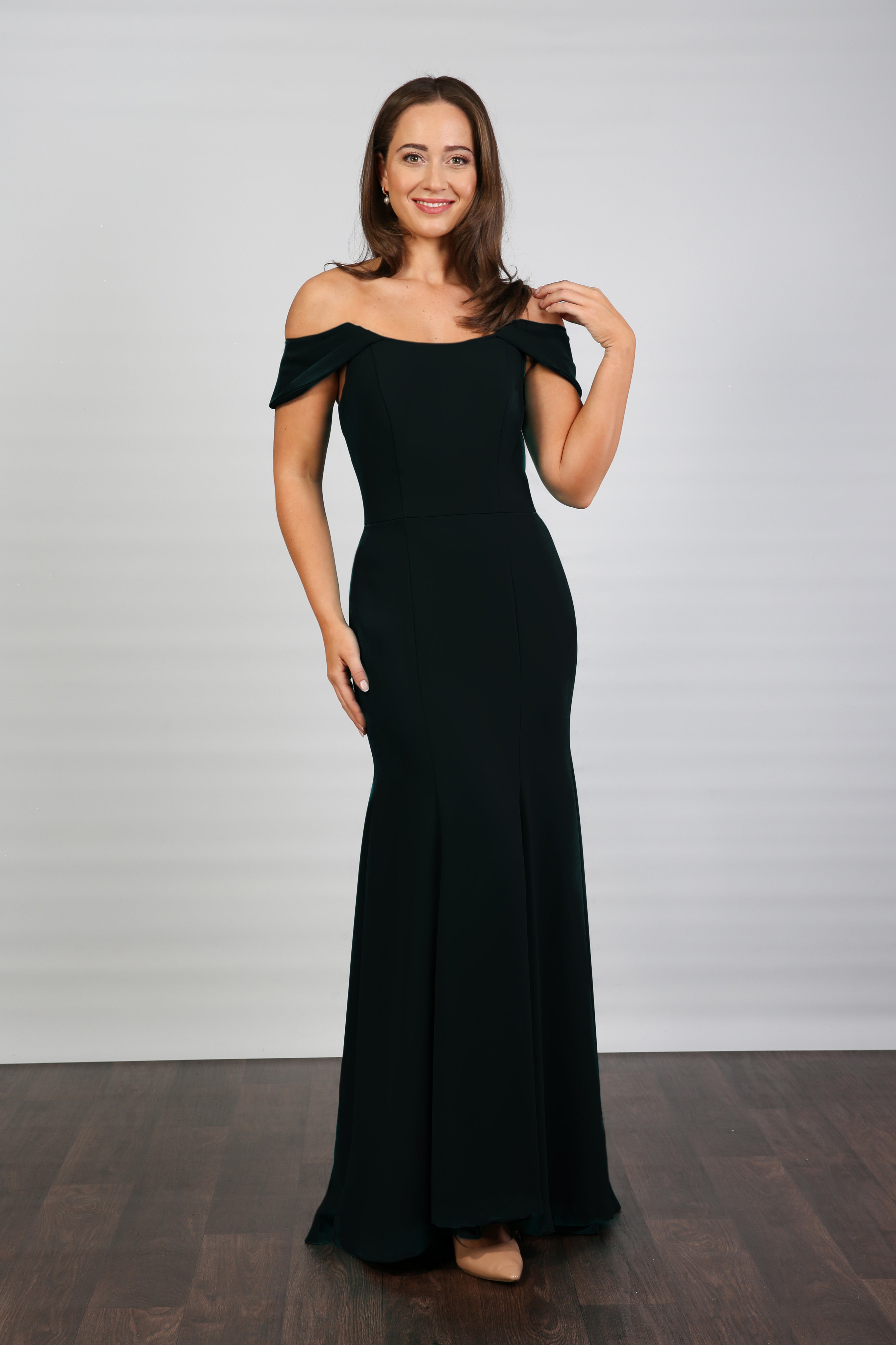 Woman wearing a black off-shoulder gown against a plain background