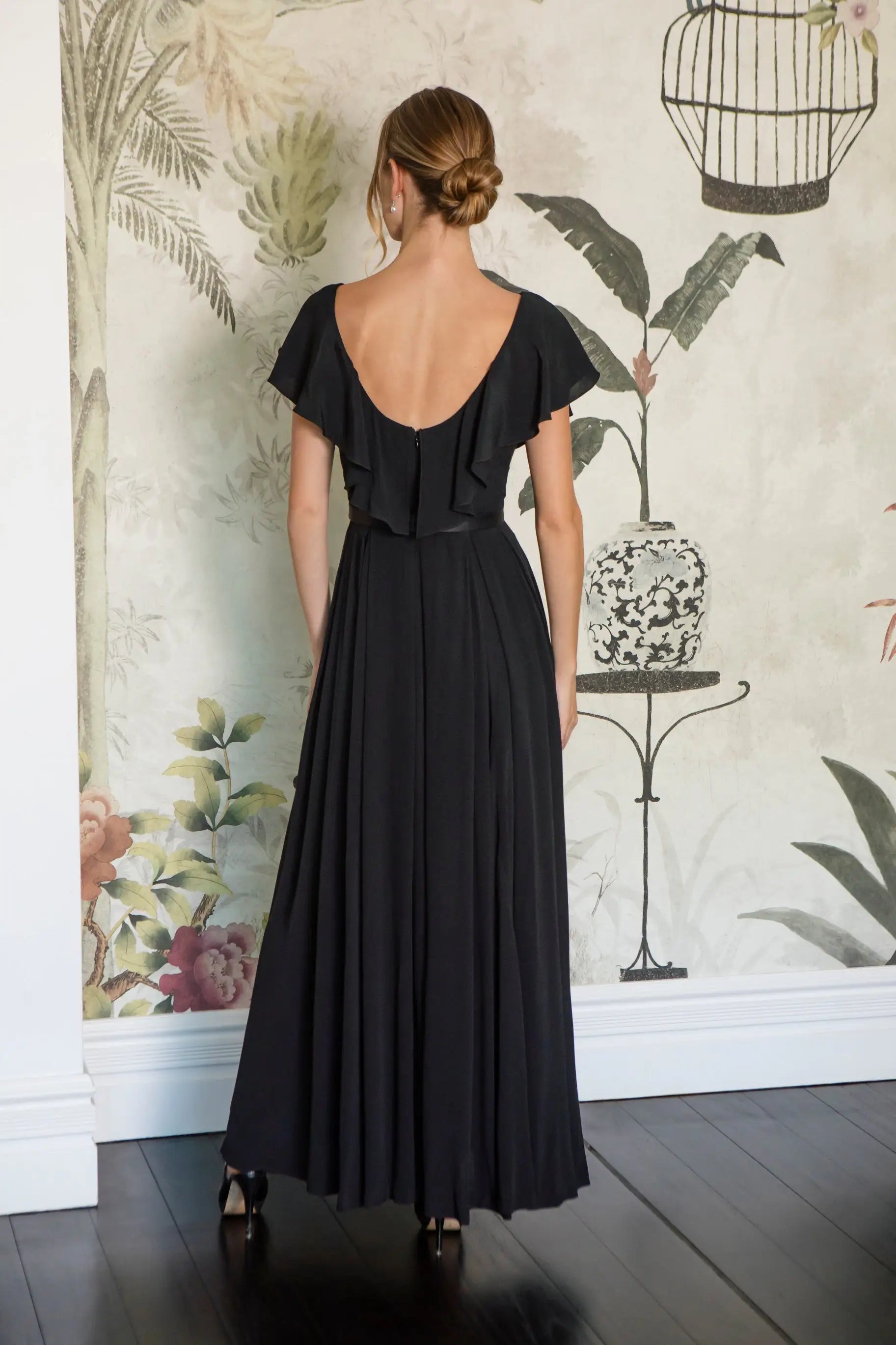 Woman wearing a black dress with a floral wallpaper background