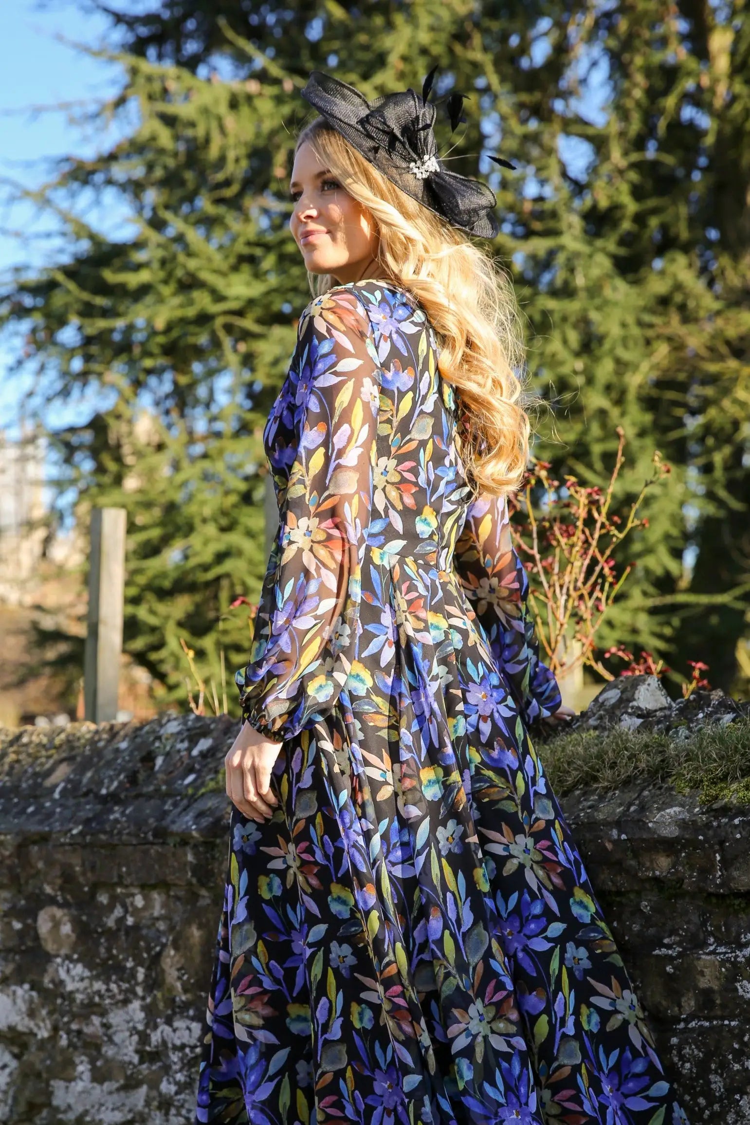 A woman standing outdoors wearing a floral printed chiffon midi dress with long sleeves and a round neckline.