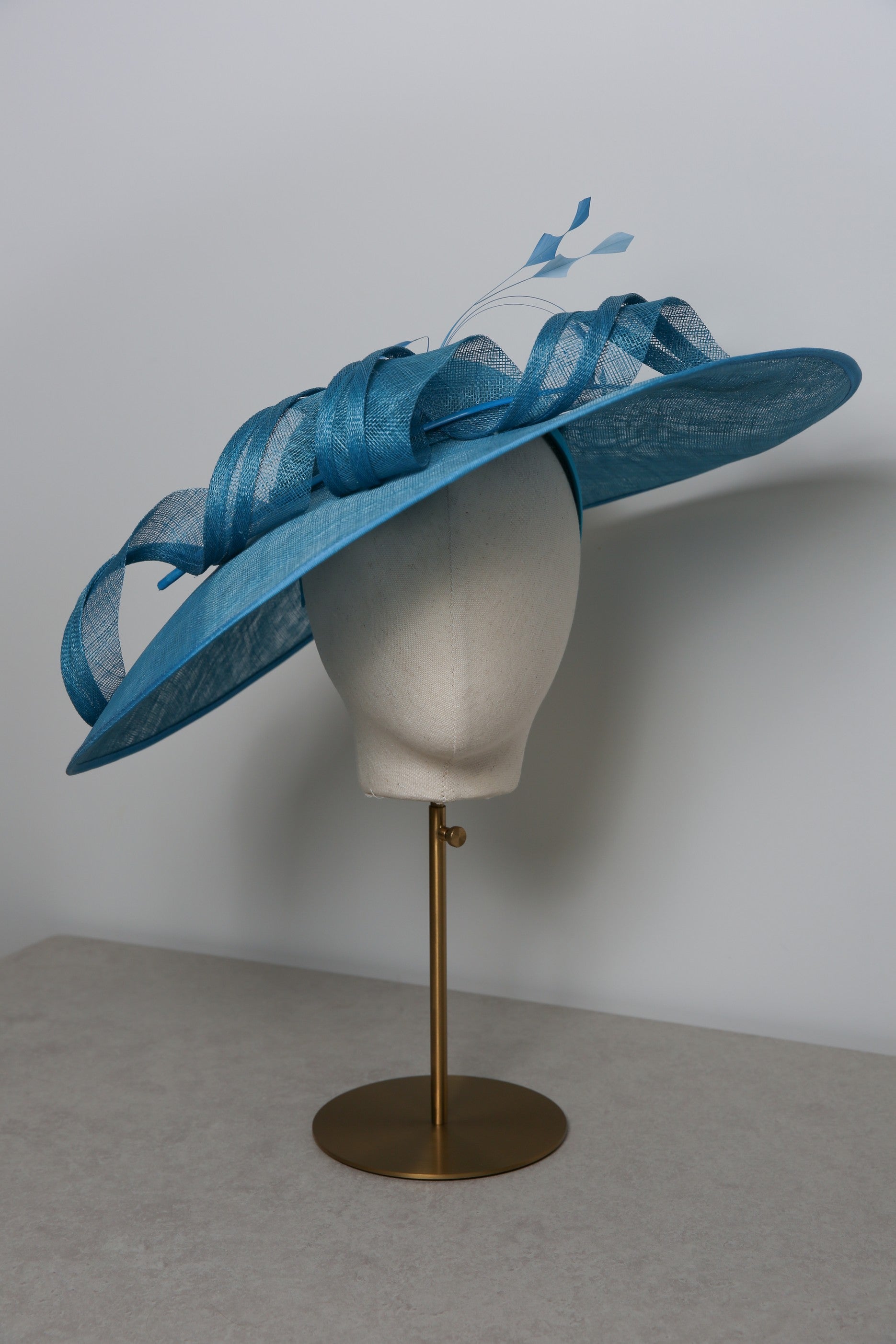 Blue decorative hat on a mannequin head against a plain background