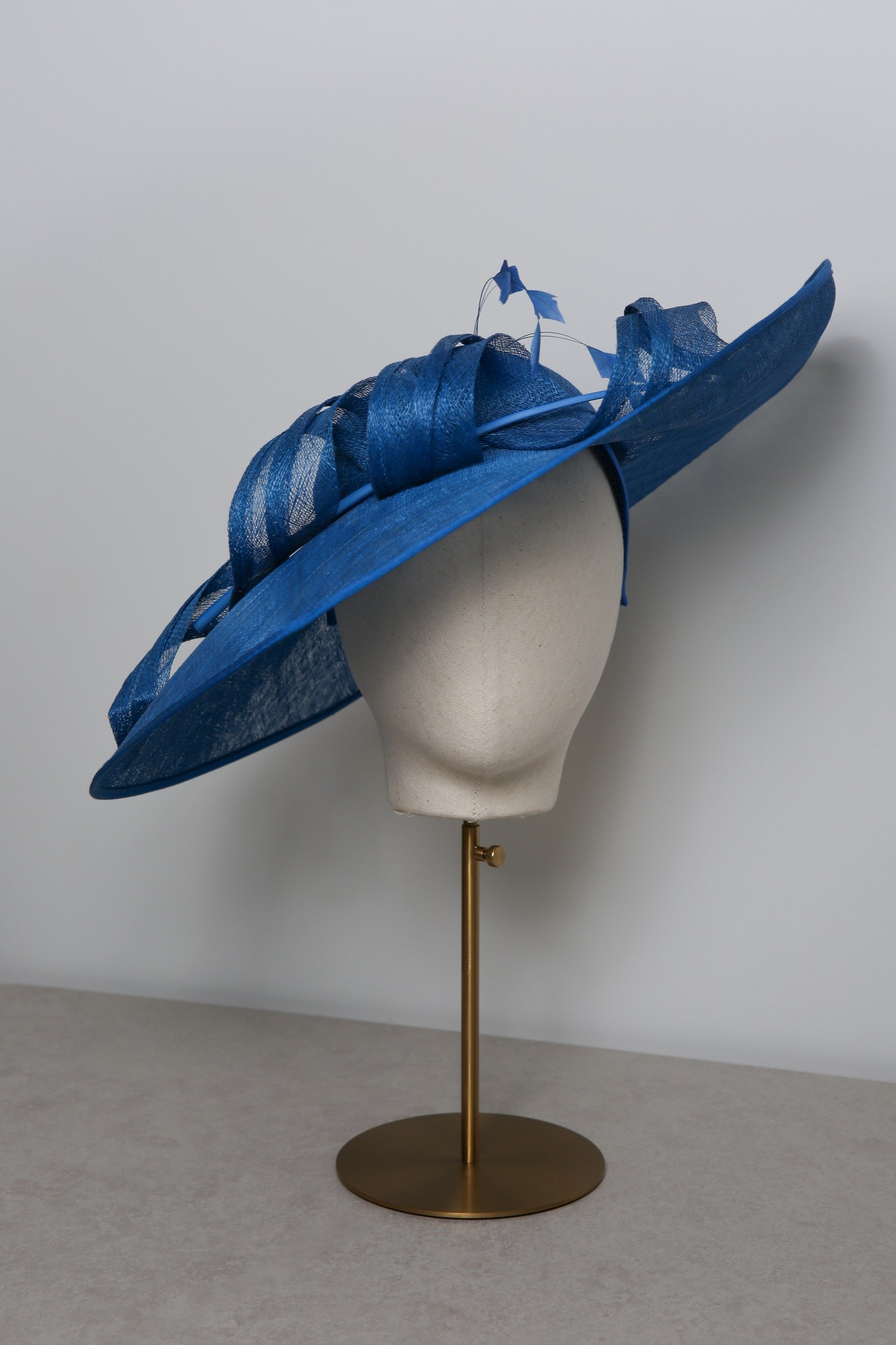 Blue decorative hat on a mannequin head against a plain background