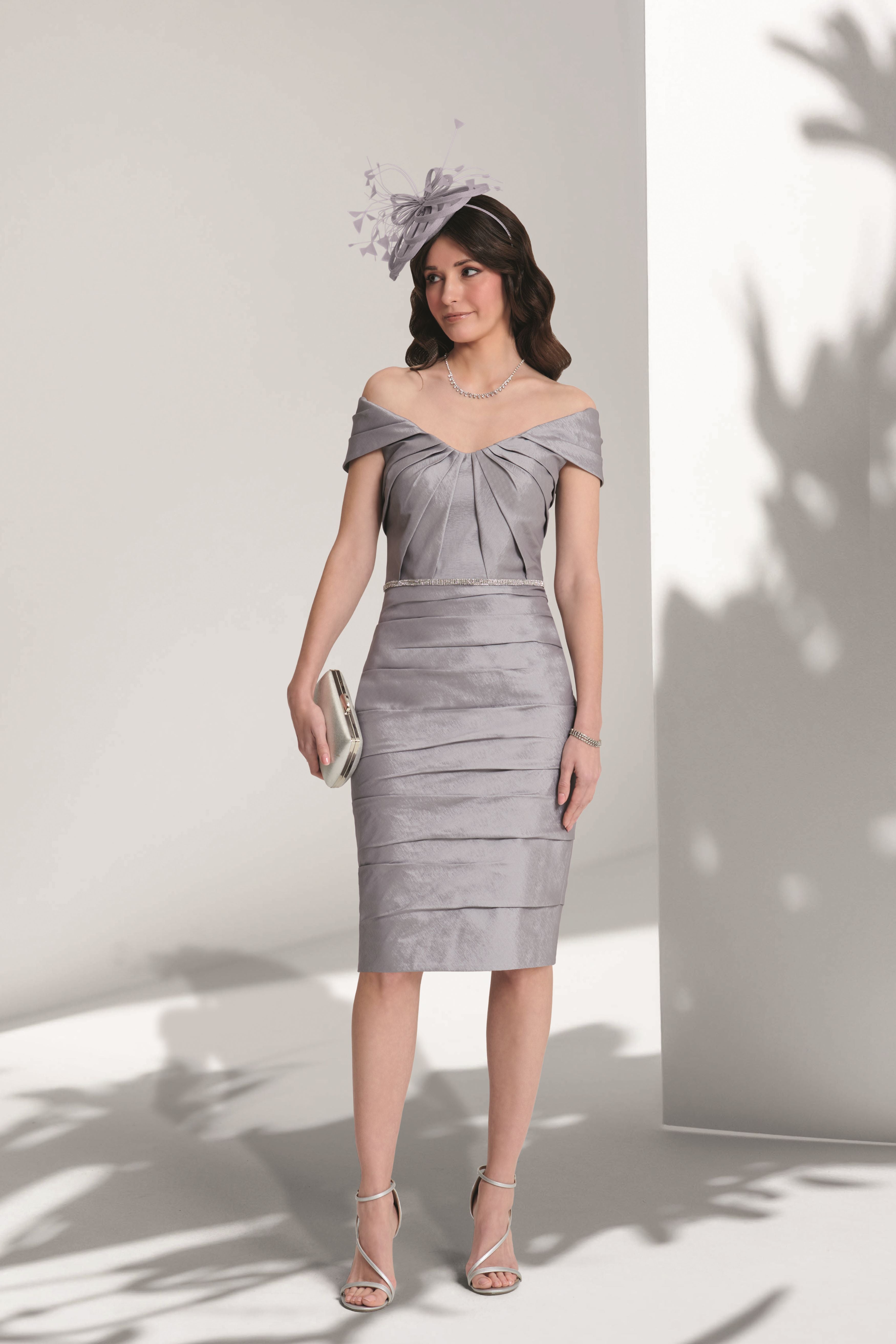 Woman wearing a silver off-shoulder dress against a white background