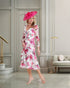 Woman wearing a floral dress and pink hat in an elegant interior setting
