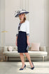 Woman in a navy and white dress with a matching hat in an elegant room.