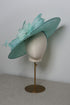 Seafoam hat with decorative elements on a mannequin head against a plain background
