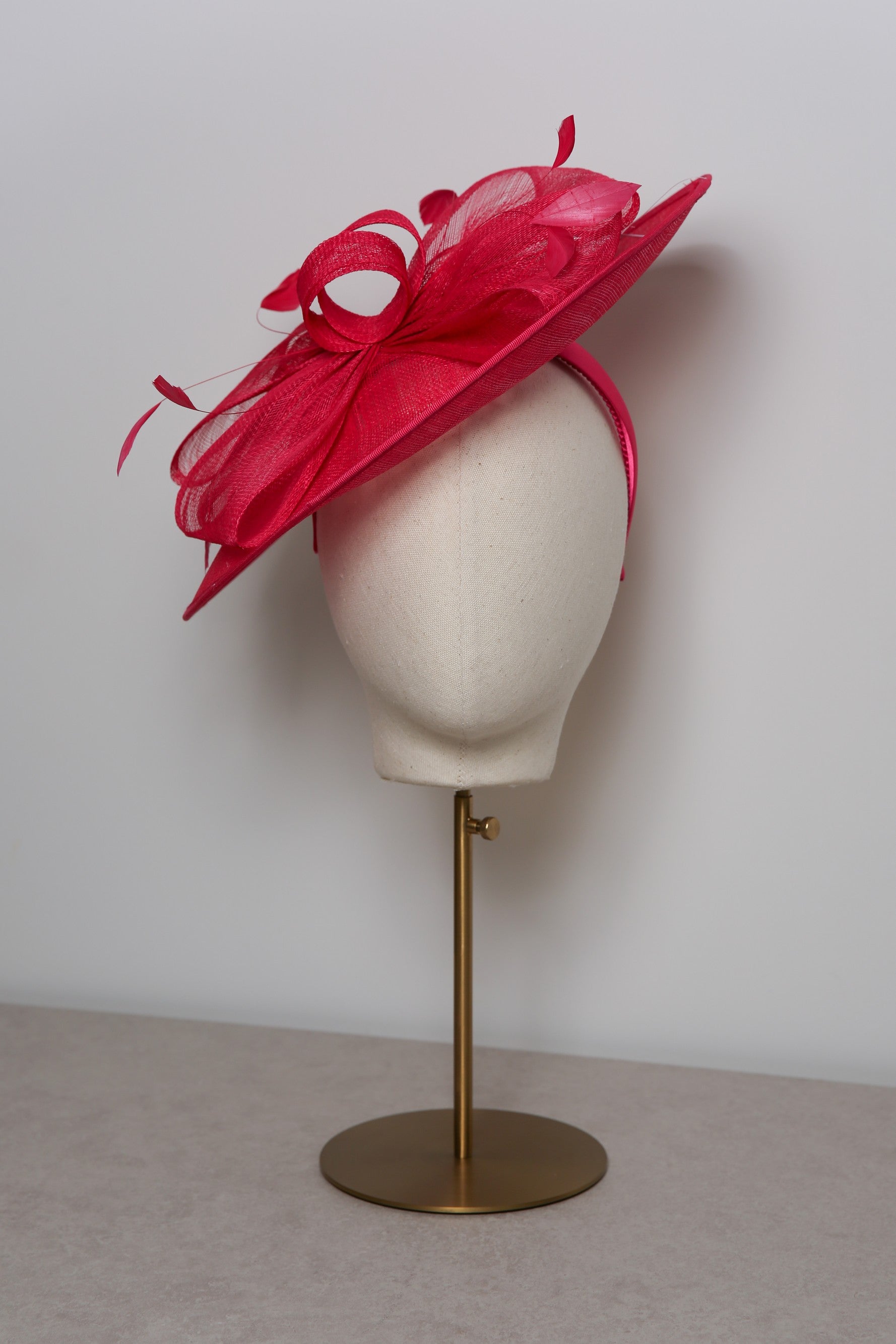 Pink decorative hat on a mannequin head against a plain background