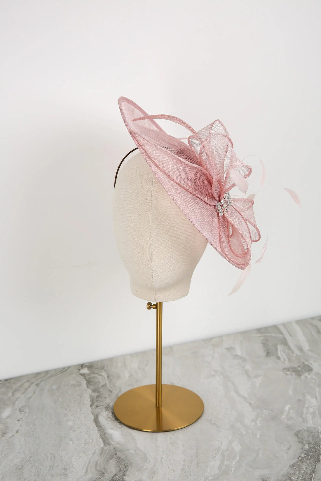 Pink fascinator on a mannequin head against a white background