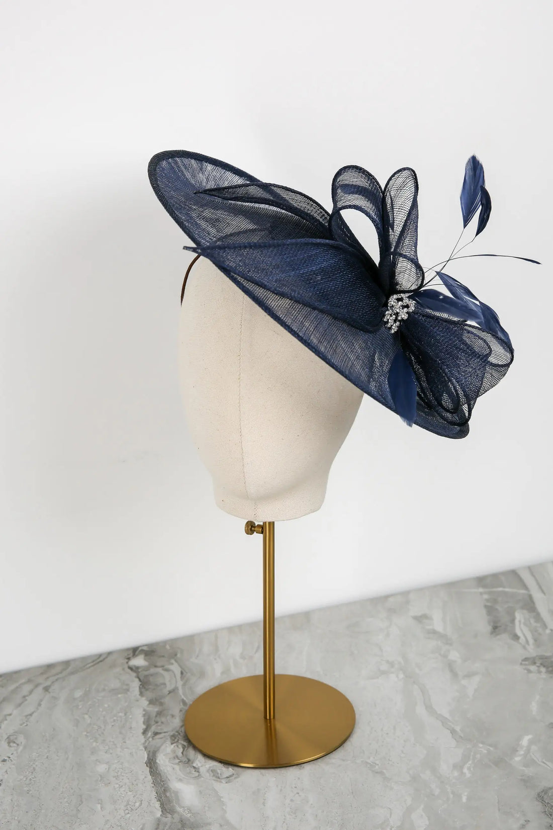 Navy blue fascinator on a mannequin head against a white background