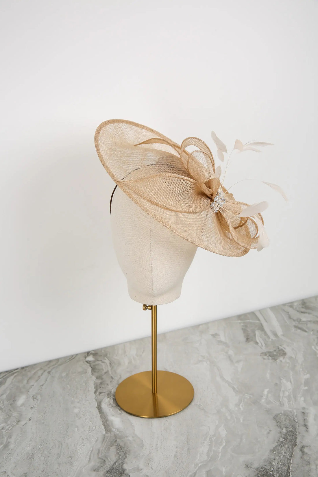 Beige decorative hat on a mannequin head against a white background