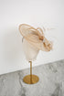 Beige decorative hat on a mannequin head against a white background