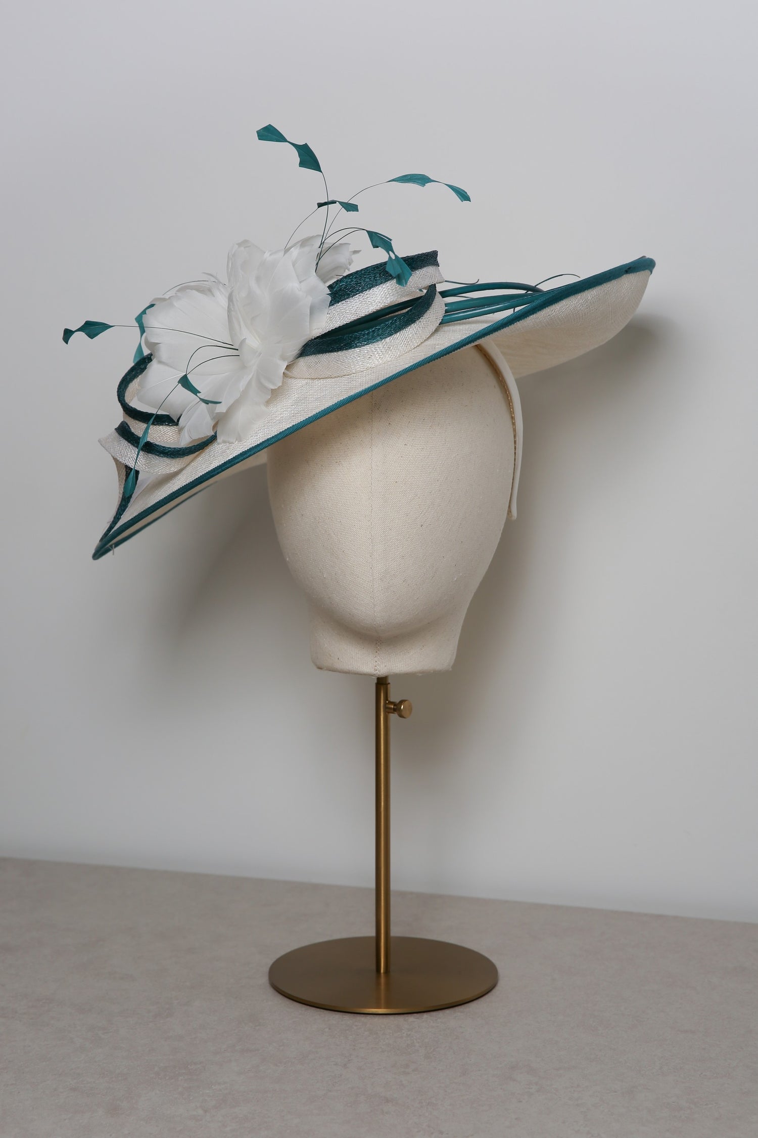 White and green decorative hat on a mannequin head against a plain background