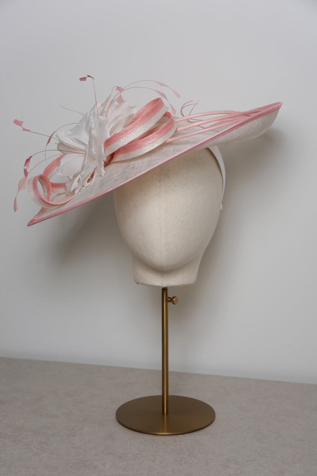 White and pink decorative hat on a mannequin head against a white background