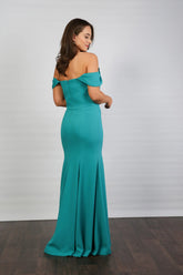 A woman in an off-the-shoulder turquoise maxi dress with a fit and flare silhouette, made from crepe fabric, posed against a neutral background.
