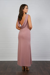 A model wearing a sleeveless, V-neck, dusty rose maxi dress with a deep cowl back and pleated waist, suitable for day to evening events.