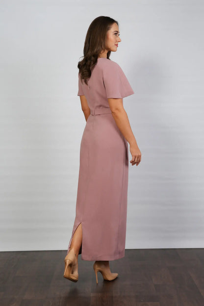 A woman models an ankle-length dress in a dusty rose colour, featuring a round neckline, short sleeves, and a back zip fastening.