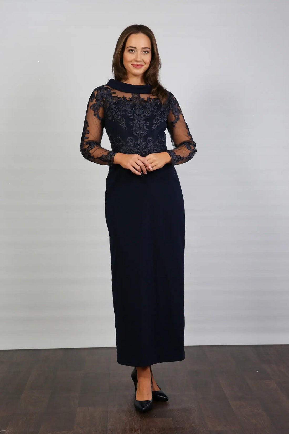 A woman in a midnight blue long-sleeved evening dress with embroidery.