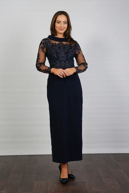 A woman in a midnight blue long-sleeved evening dress with embroidery.