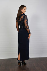 A woman in a midnight blue long-sleeved evening dress with embroidery.