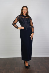 A woman in a midnight blue long-sleeved evening dress with embroidery.