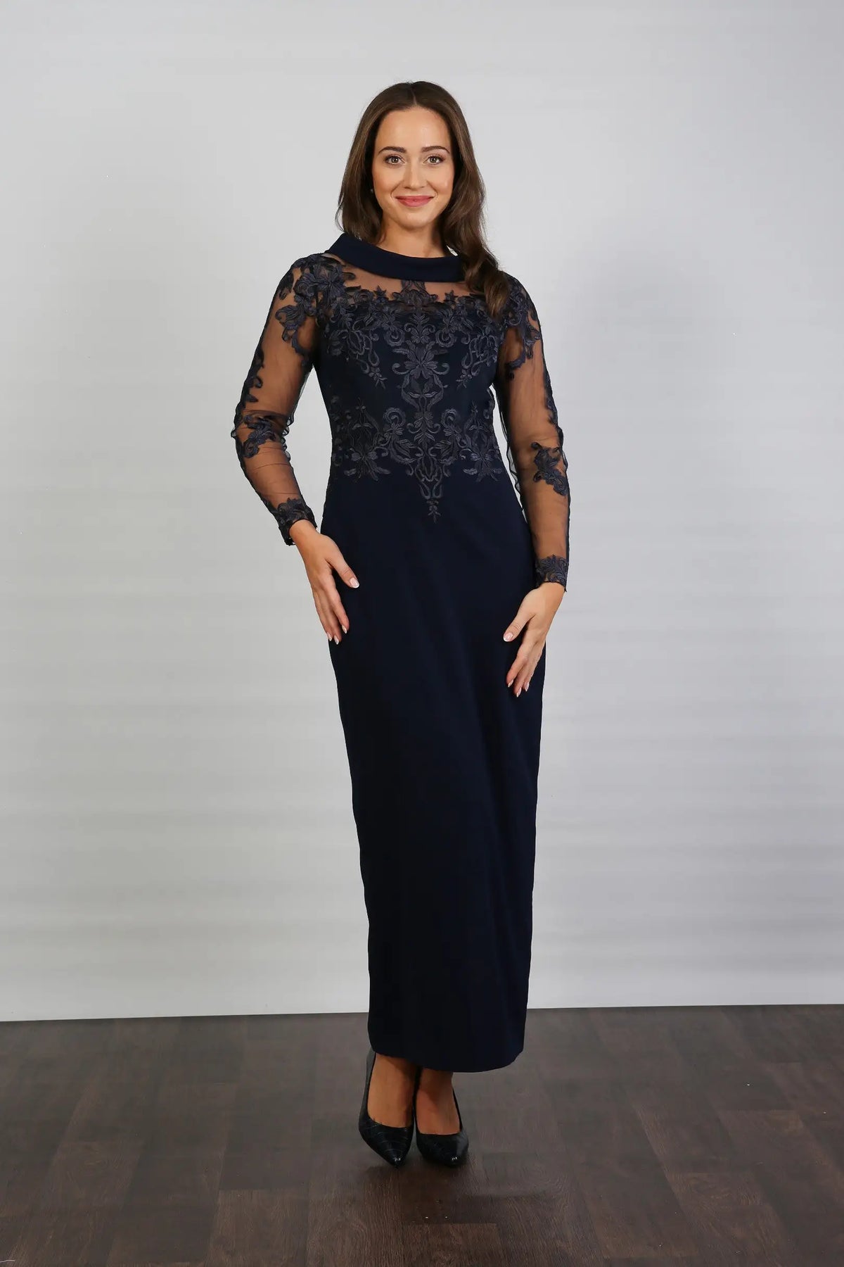 A woman in a midnight blue long-sleeved evening dress with embroidery.