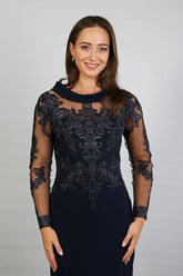 A woman in a midnight blue long-sleeved evening dress with embroidery.