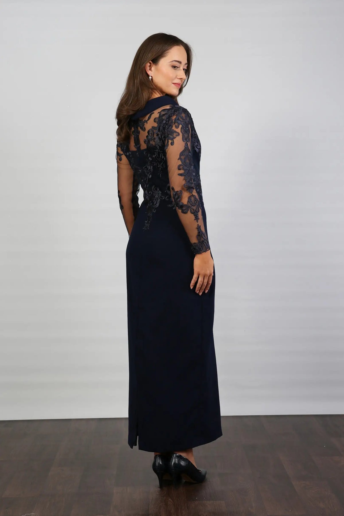 A woman in a midnight blue long-sleeved evening dress with embroidery.