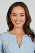 A woman wearing a light blue dress with a floral pattern and Chalcedony Pearl Stud Drop Earrings.