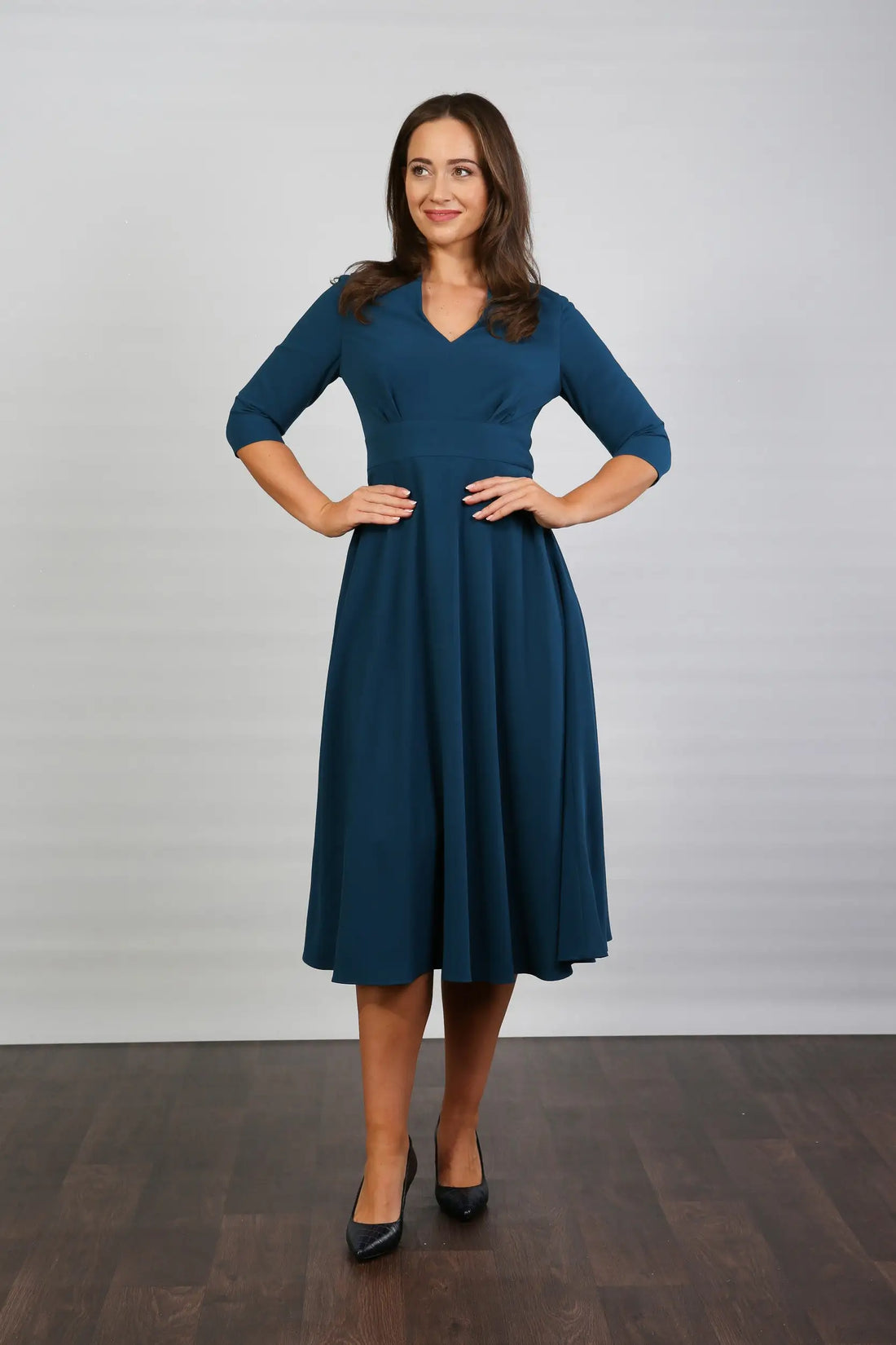 A model wearing a midi-length blue crepe dress with a V-neck, 3/4 sleeves, and a fitted waist.