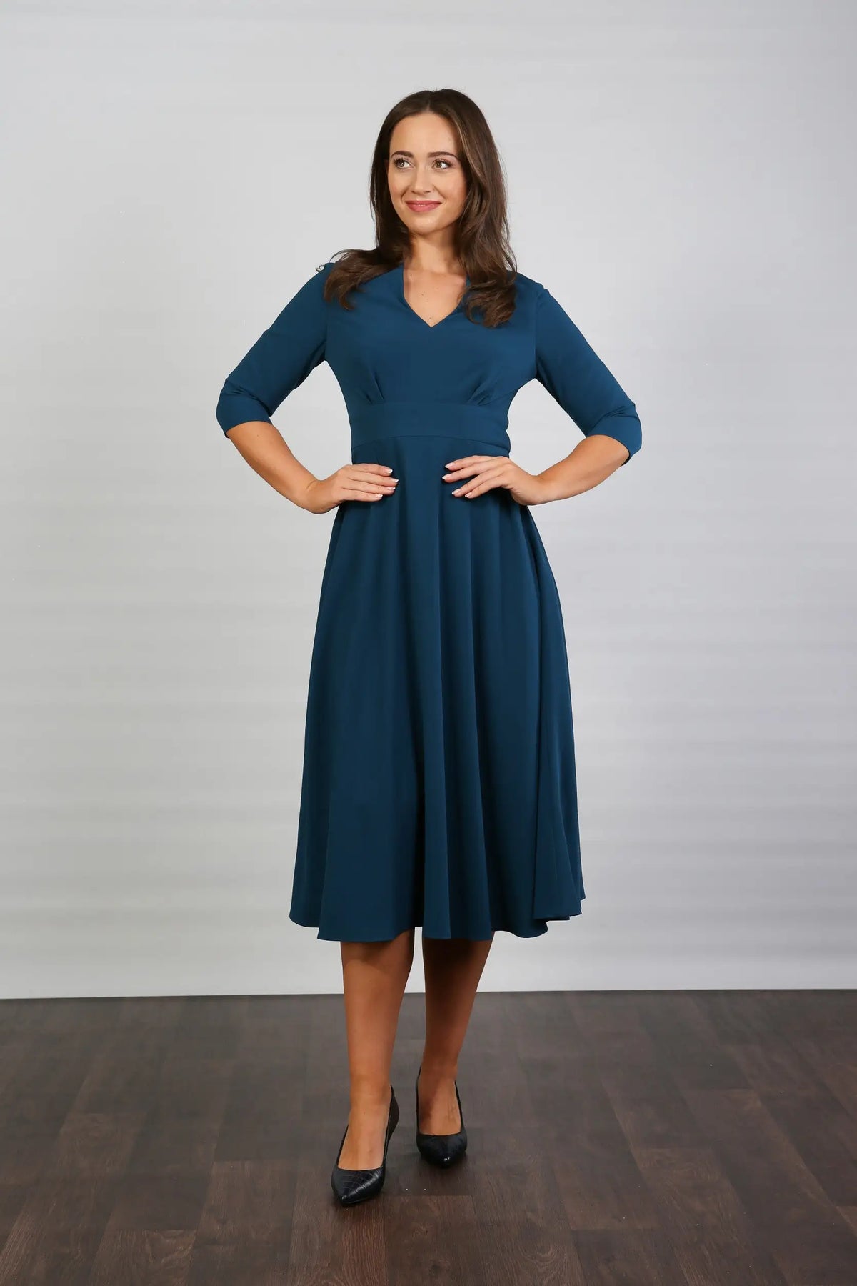 A model wearing a midi-length blue crepe dress with a V-neck, 3/4 sleeves, and a fitted waist.