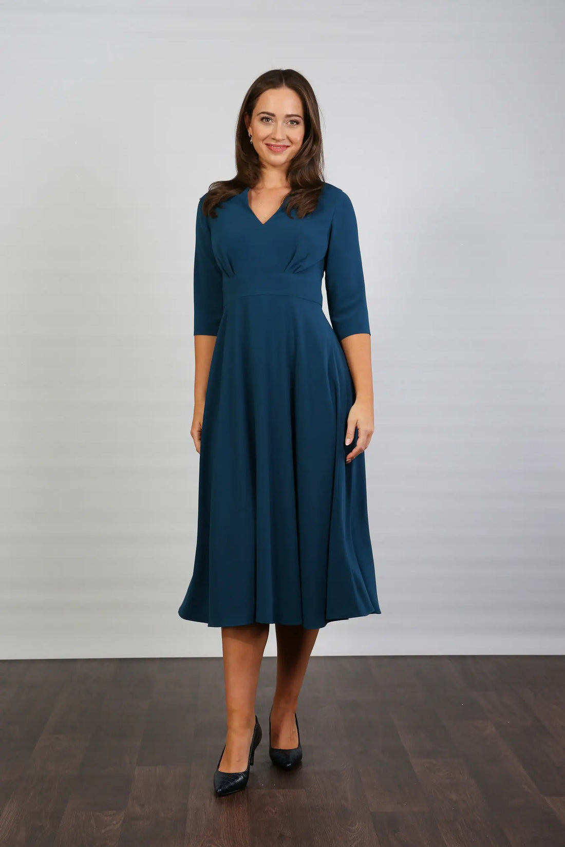 A model wearing a midi-length blue crepe dress with a V-neck, 3/4 sleeves, and a fitted waist.