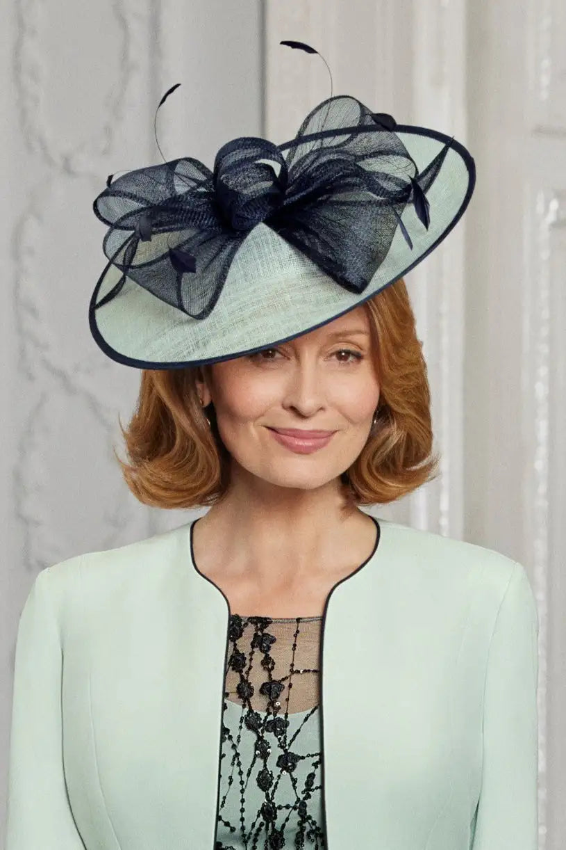 Woman wearing a stylish hat with a large bow against a neutral background