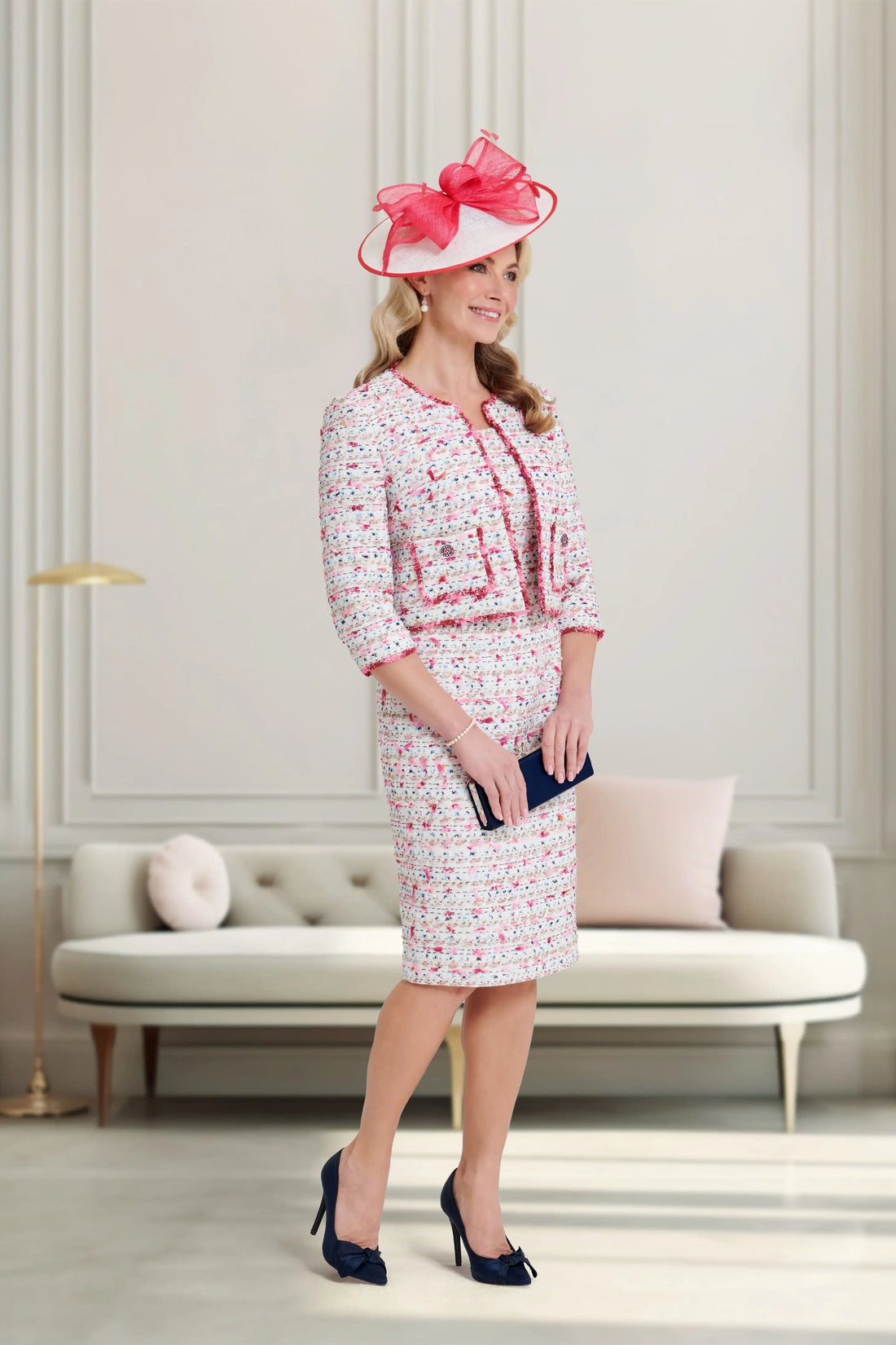 Woman in a stylish outfit with a pink hat in an elegant room.