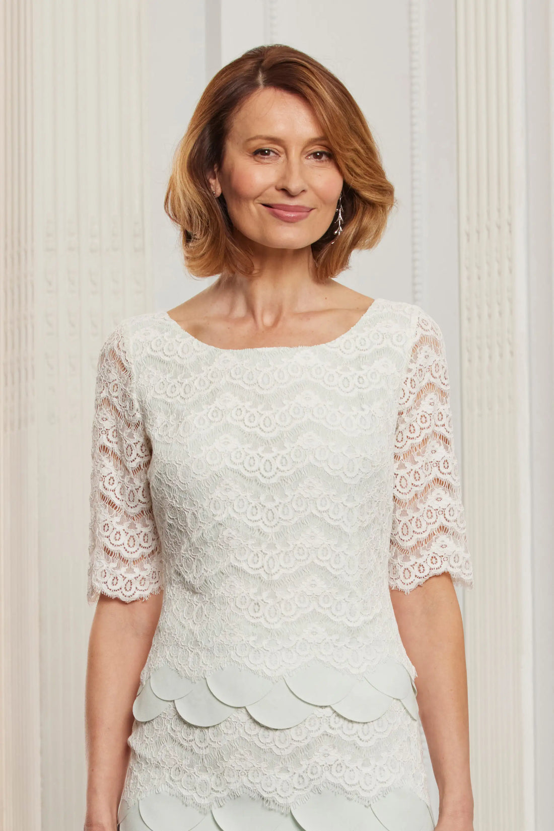 A woman wearing a light green scallop lace occasion dress.
