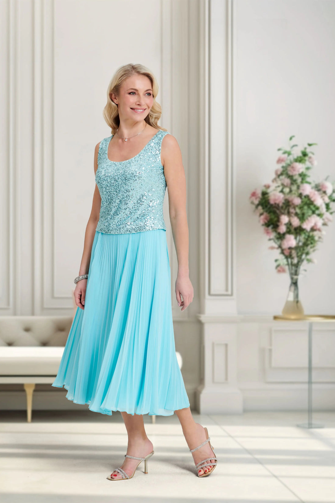 Woman wearing a light blue dress with a floral top in an elegant room.