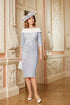 Woman in a light blue dress with white lace details and a matching hat standing in an ornate room.