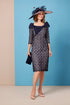 A model wearing a navy shift silhouette dress with a geometric pattern, featuring long sleeves and a bow detail on the neckline. The dress is fully lined and finishes below the knee.