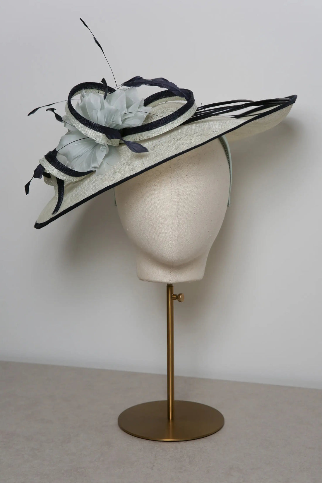 Mint and navy decorative hat on a mannequin head against a plain background