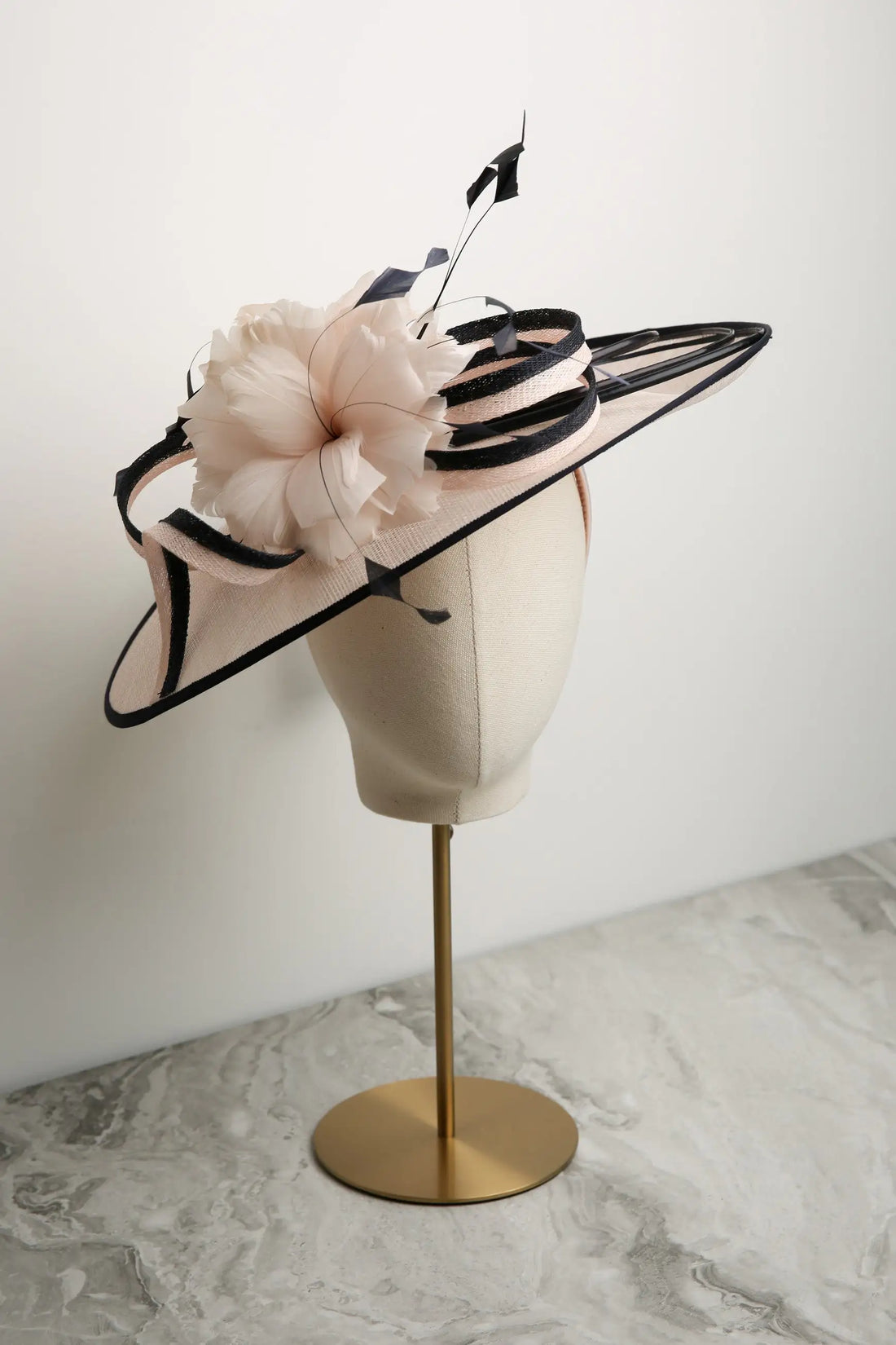Pink and navy decorative hat on a mannequin head against a white background