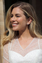 A pair of crystal halo stud earrings, with the earrings themselves having a large central clear crystal surrounded by smaller clear crystals.