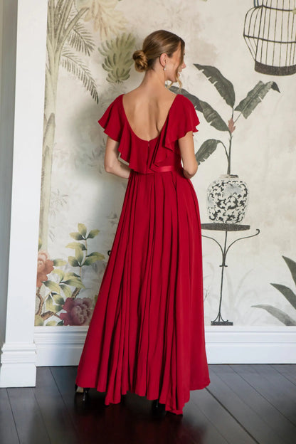 Woman wearing a red dress with a floral wall and decorative elements in the background