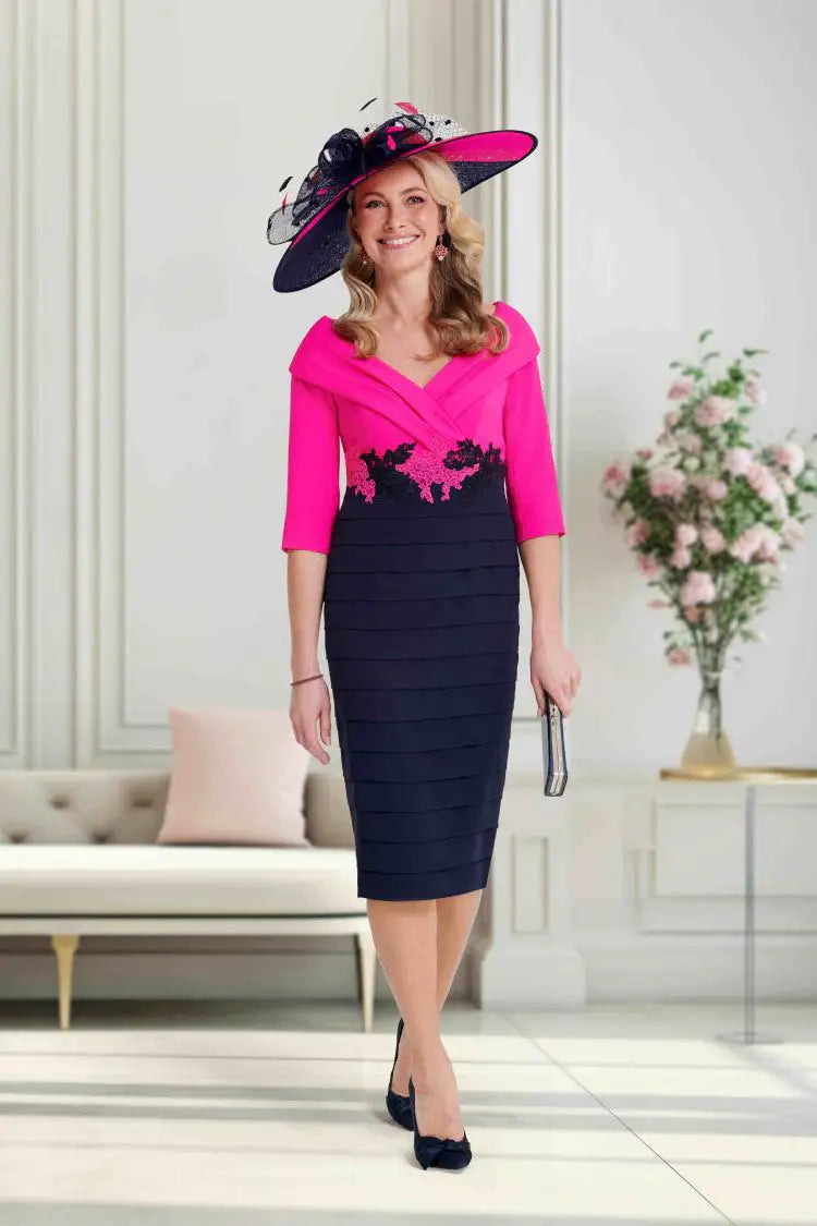 Woman wearing a pink and navy dress with a matching hat in an elegant room.