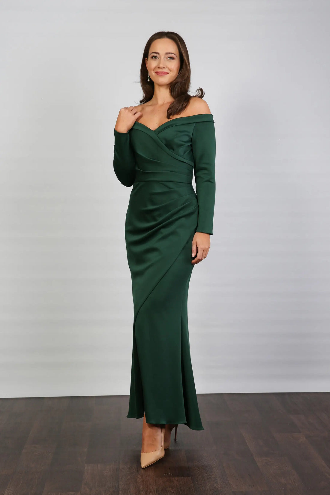 A woman models an off-the-shoulder, long-sleeved, green stretch jersey evening dress.