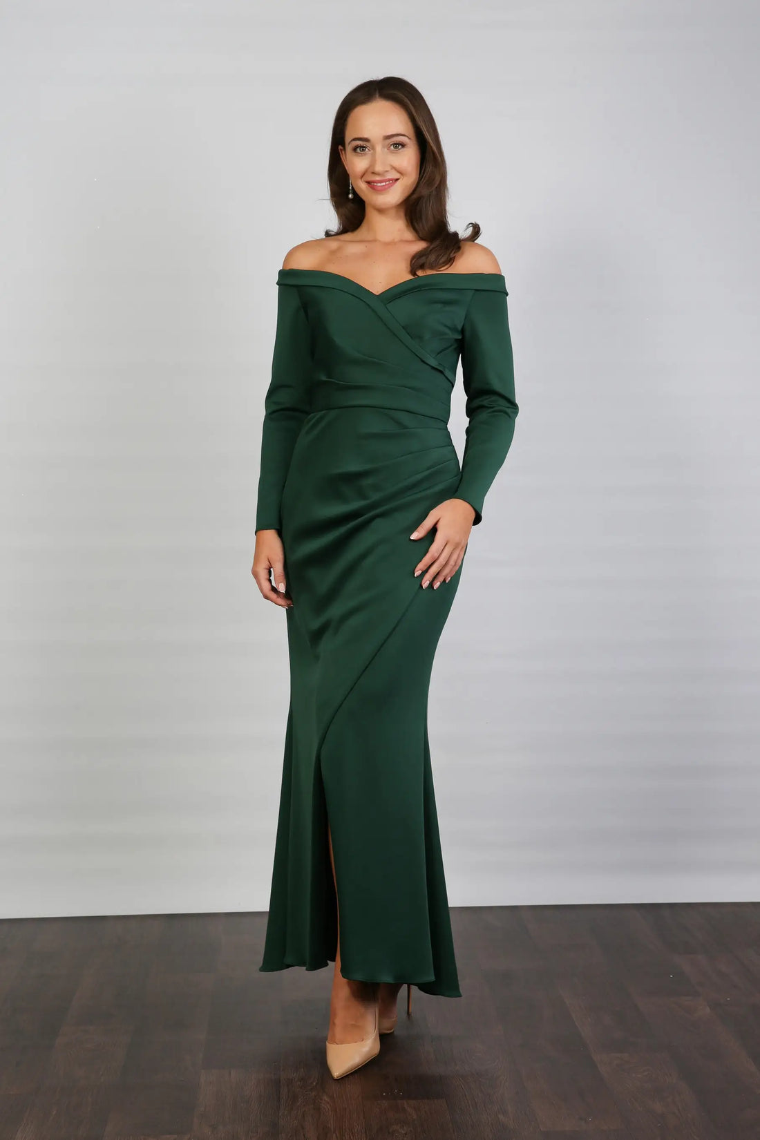 A woman models an off-the-shoulder, long-sleeved, green stretch jersey evening dress.
