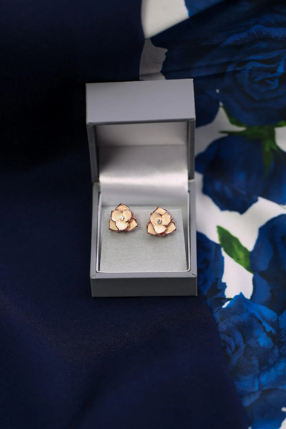 Rose gold floral earrings in a box with a floral background