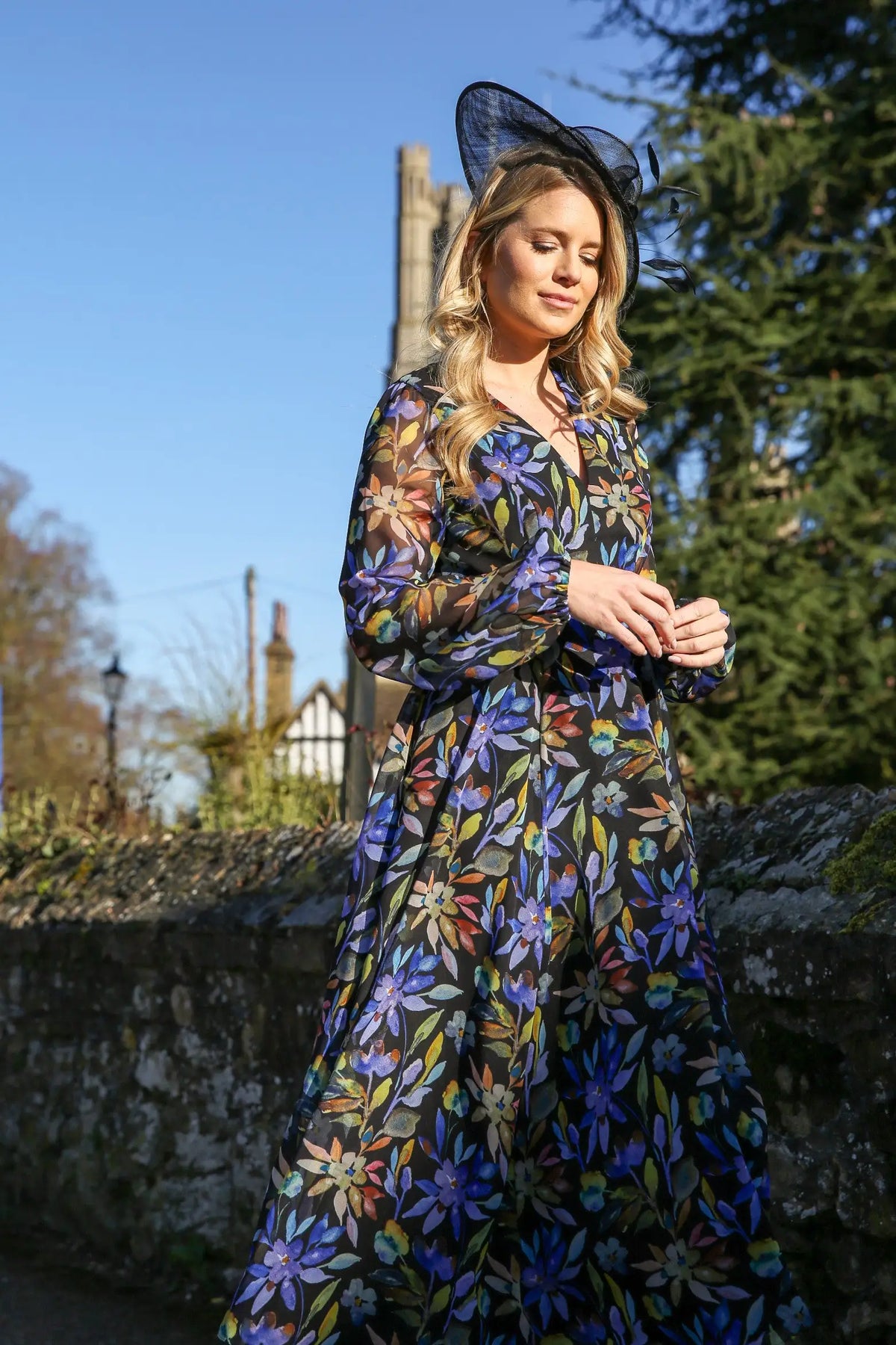 A woman standing outdoors wearing a floral printed chiffon midi dress with long sleeves and a round neckline.
