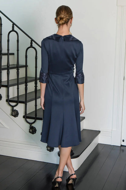 Woman in a navy dress standing on a staircase