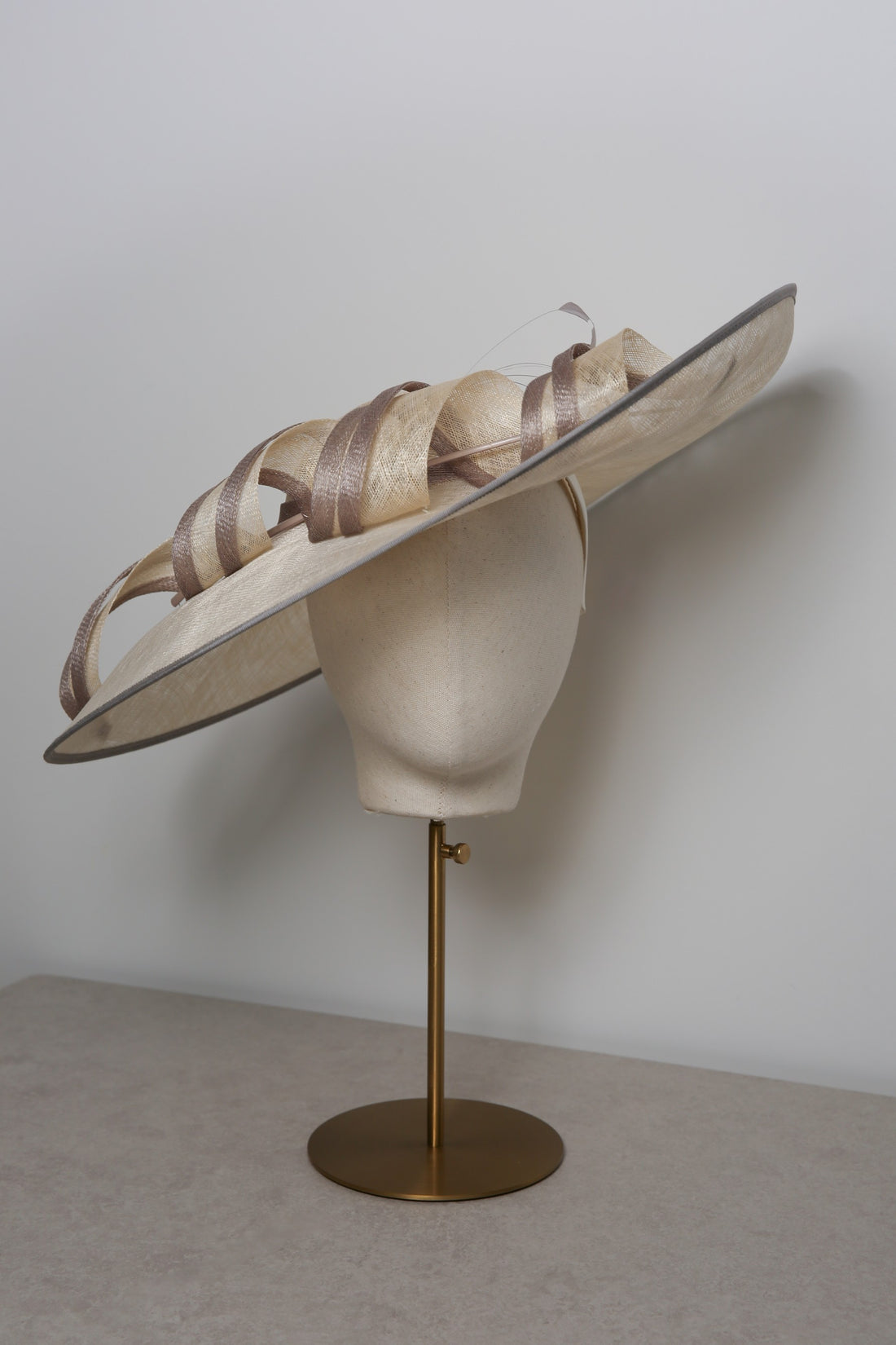 Large decorative hat on a mannequin head with a plain background