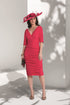 Woman wearing a red dress and hat against a white wall