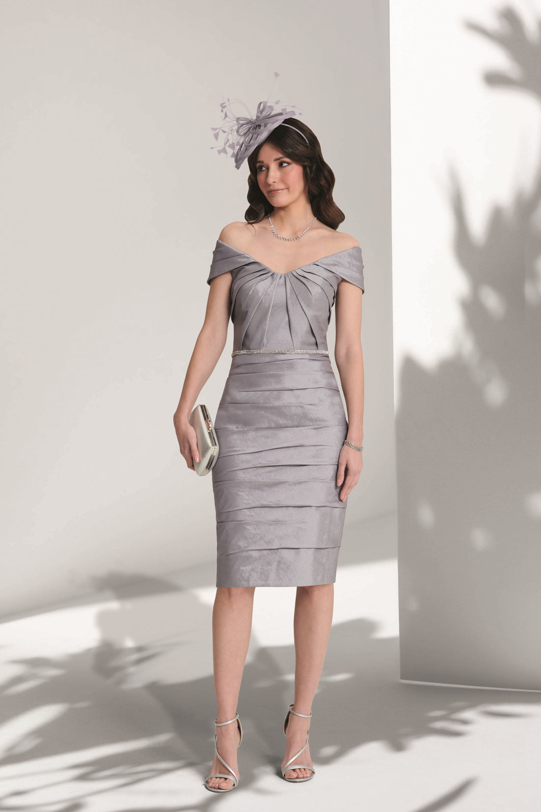 Woman wearing a silver off-shoulder dress against a white background